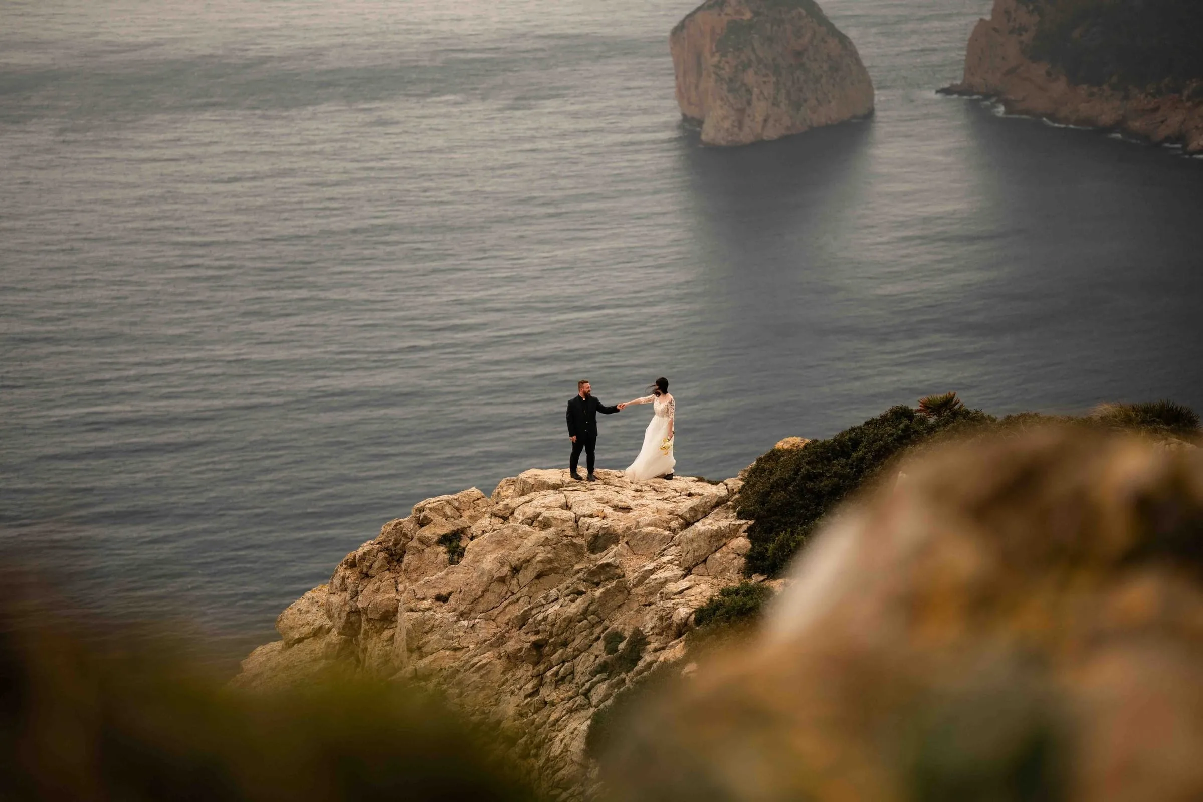 Brautpaar Hand in Hand auf einer Felsklippe hoch über dem Meer – Elopement