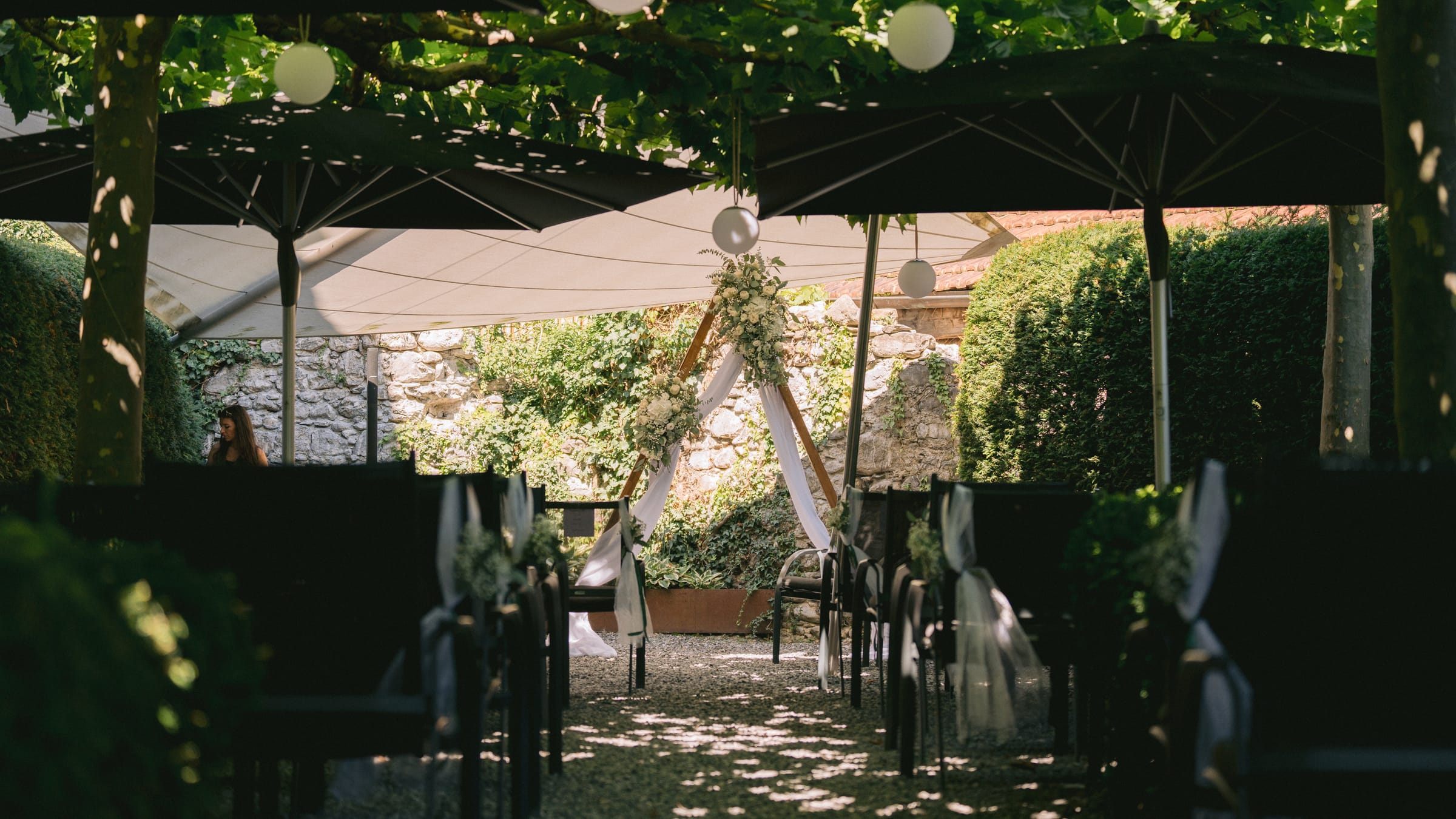 Freie Trauung unter der Reben-Pergola im Schloss Maienfeld mit Blumenbogen und Lampions im Schatten