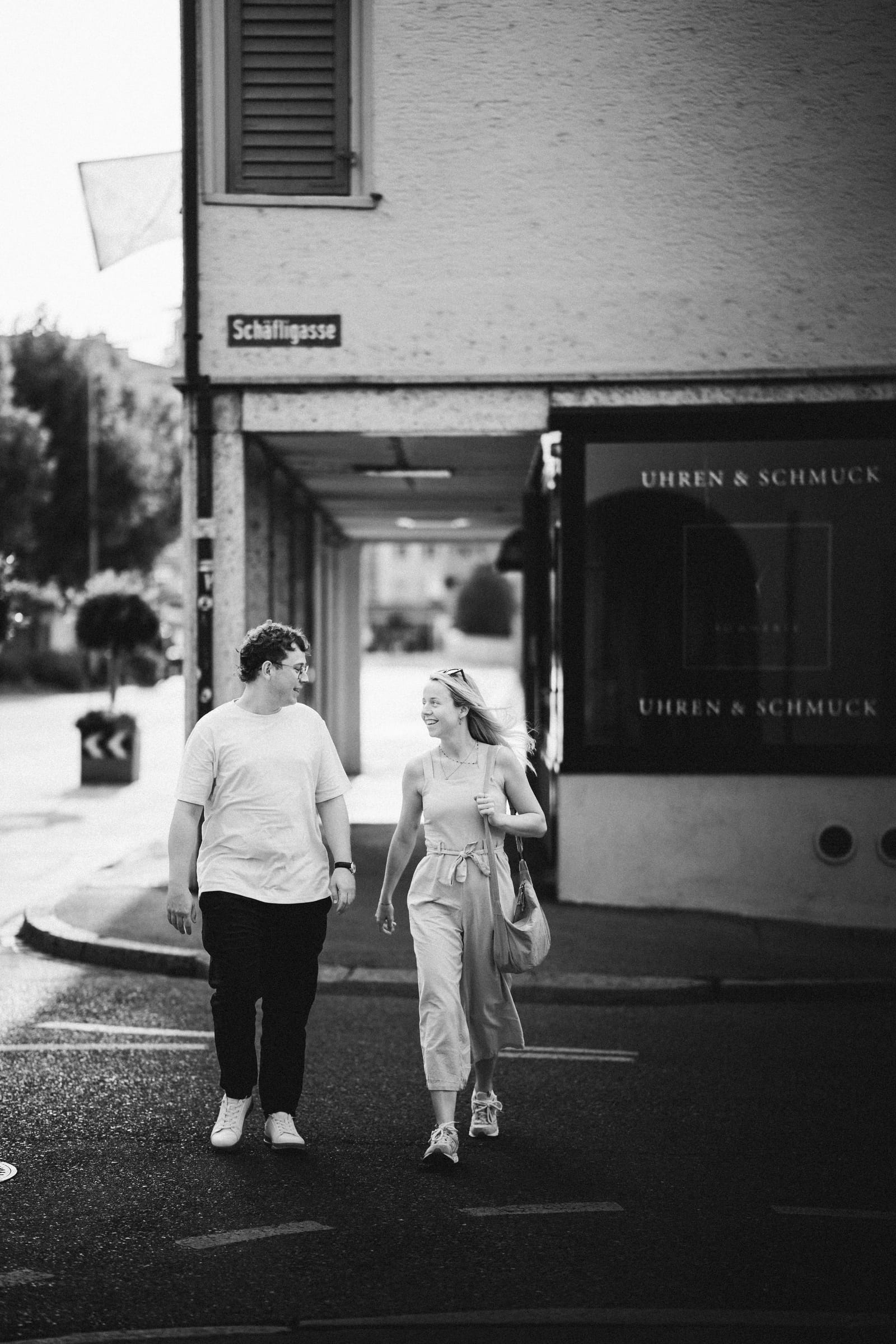 Natalie und Luca gehen lachend über eine Strasse in der Altstadt von Arbon, Schwarzweiss, Strassenschild Schäfligasse