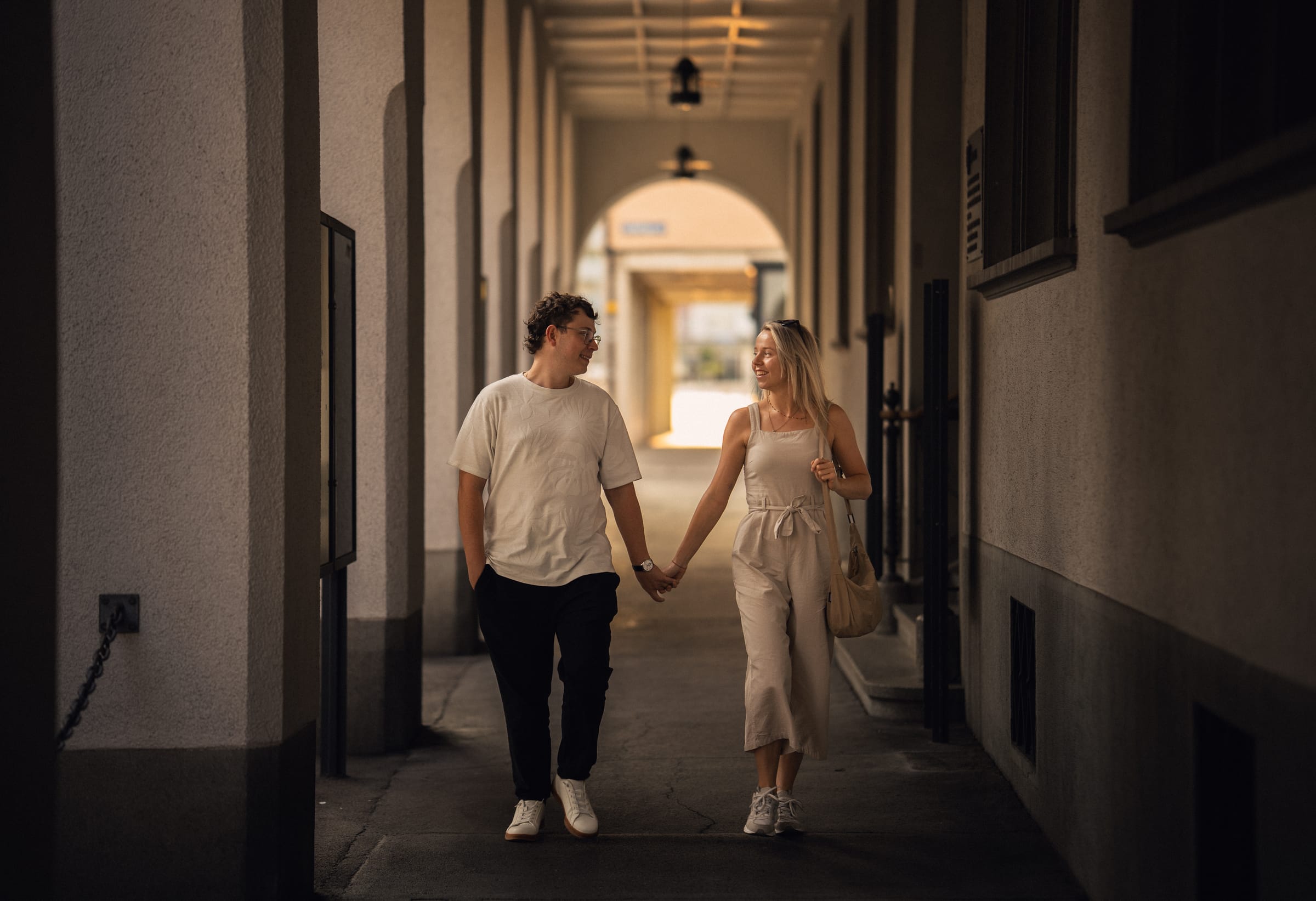 Natalie und Luca gehen Hand in Hand durch einen Arkadengang in der Altstadt von Arbon