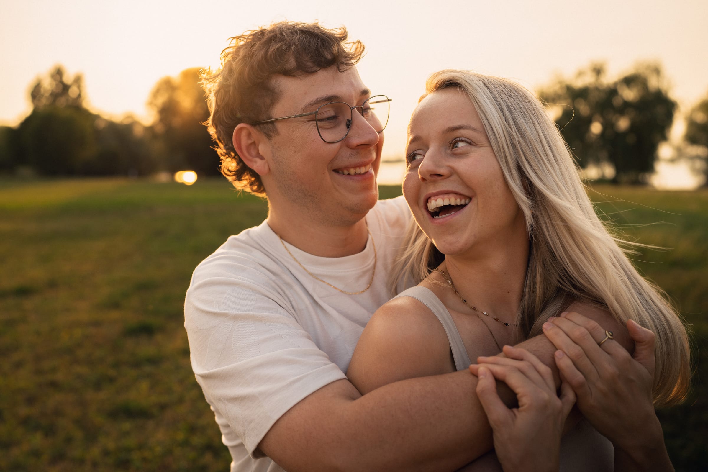 Natalie und Luca lachen laut, eng umschlungen auf der Wiese in Arbon