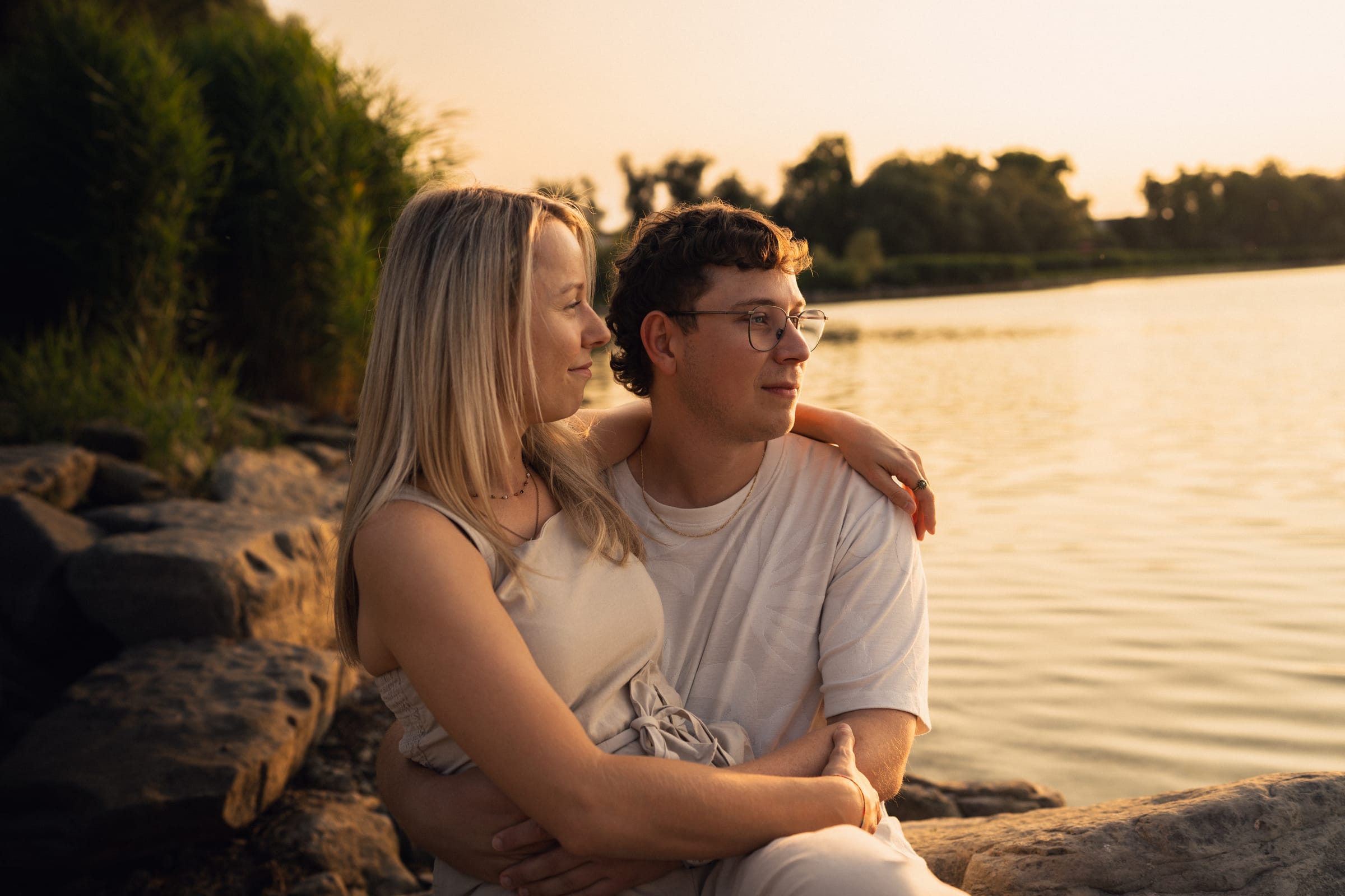 Natalie und Luca sitzen auf den Steinen am Ufer in Arbon, Schilf und See im Hintergrund