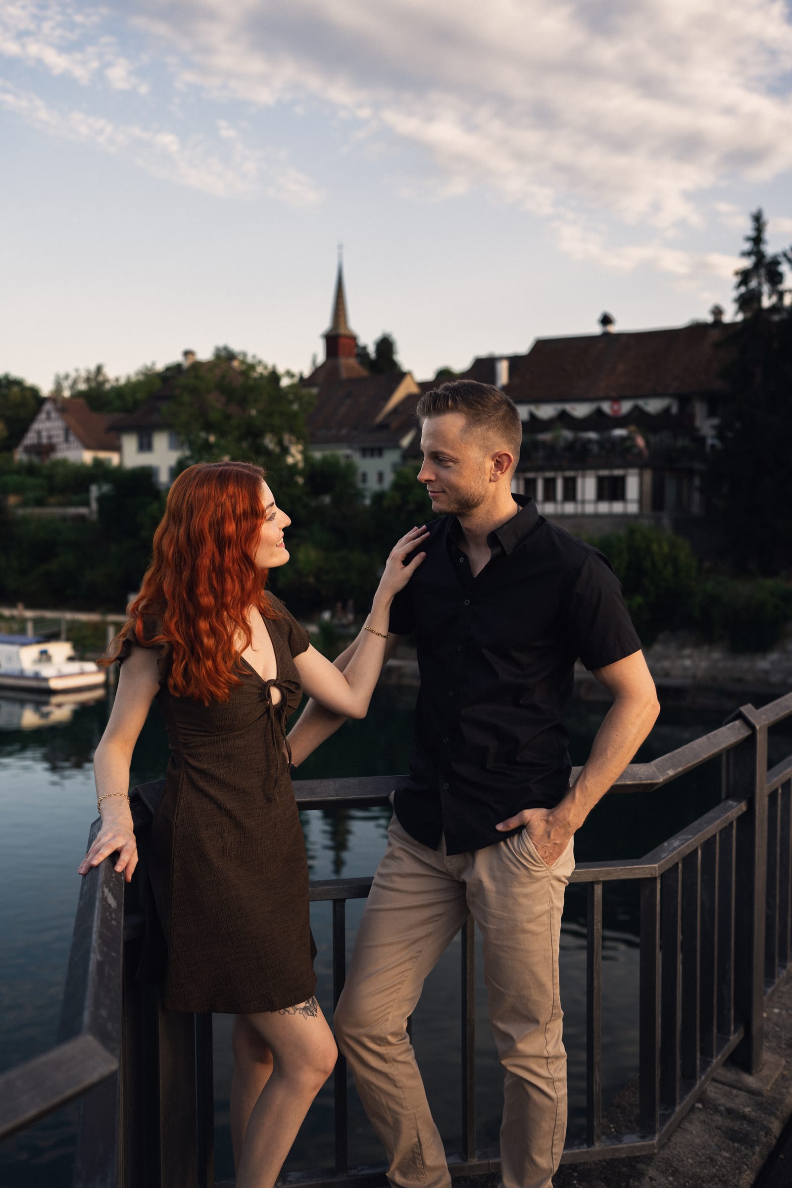Tatjana und Yanick am Geländer am Rheinufer, hinter ihnen die Altstadt von Kaiserstuhl mit Kirchturm