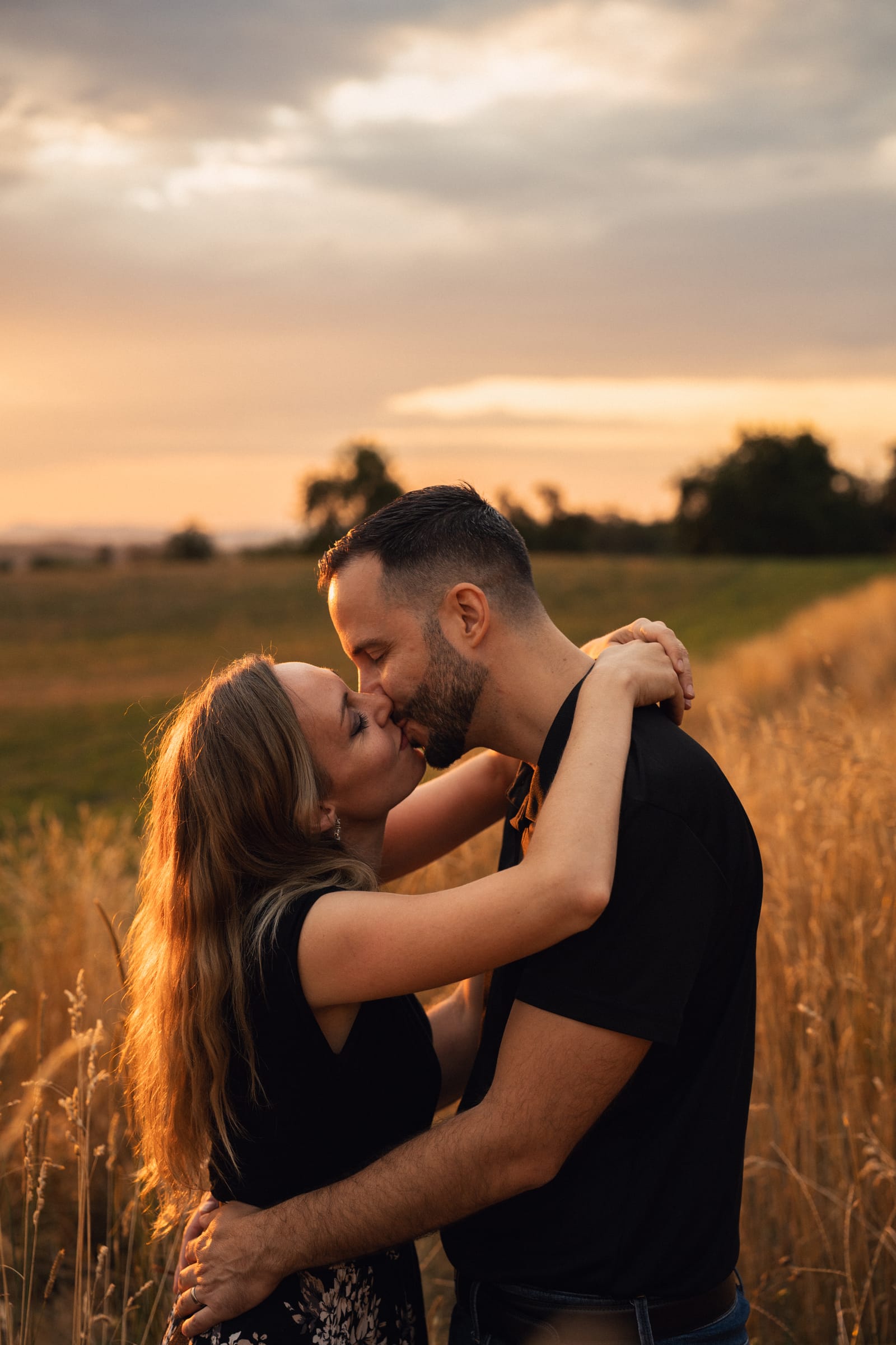 Martina und Stephan küssen sich im hohen Gras, Abendhimmel dahinter